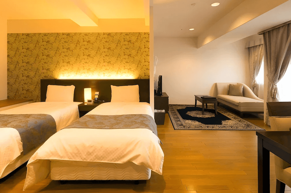 【函館住宿】函館環球景觀飯店典雅雙床房，溫暖燈光搭配壁紙設計，房內附有貴妃椅與茶几，營造高雅休憩氛圍。