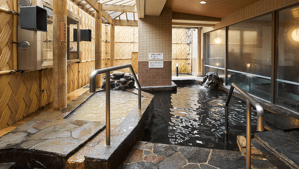 【函館住宿】函館環球景觀飯店露天溫泉池，石砌池畔搭配木質圍欄設計，讓旅客可在自然氛圍中享受溫泉療癒。