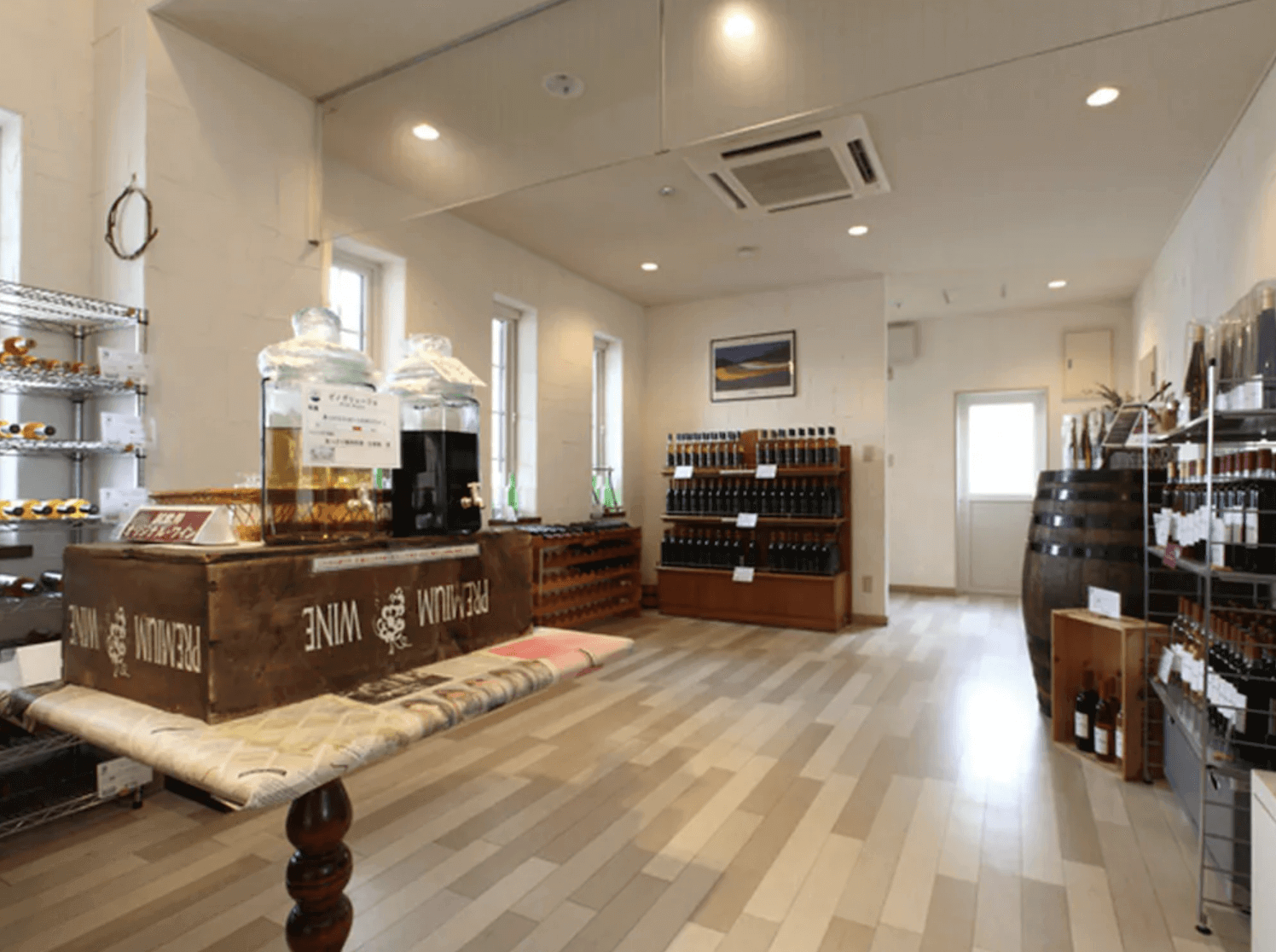 【富良野住宿】北國度假飯店 (Resort Inn North Country) 酒店內部商店空間，擺滿各式葡萄酒瓶與酒桶，中央設有試飲台，氛圍明亮整潔。