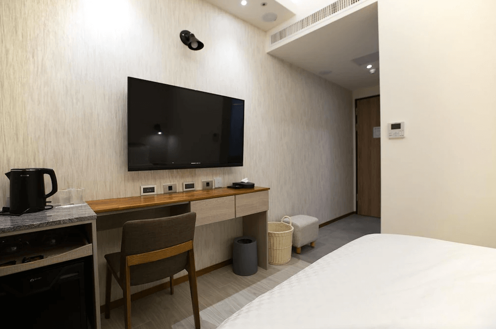 【玉里住宿】「原鄉商旅」客房內部設施，大型平面電視搭配書桌與座椅，並備有熱水壺與小冰箱，提供便利住宿體驗。