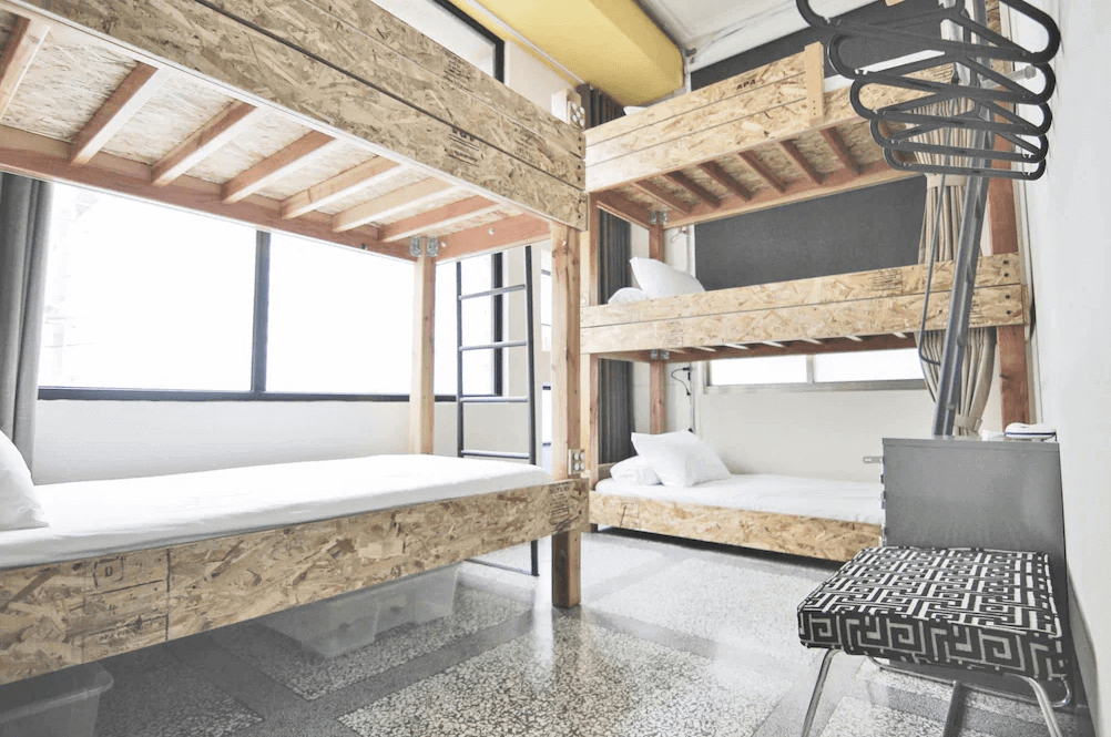 【高雄中央公園住宿】同．居 With Inn Hostel多人房：上下舖木質床架設計，寬敞明亮的空間配有大窗戶與自然採光，適合背包客與團體入住。