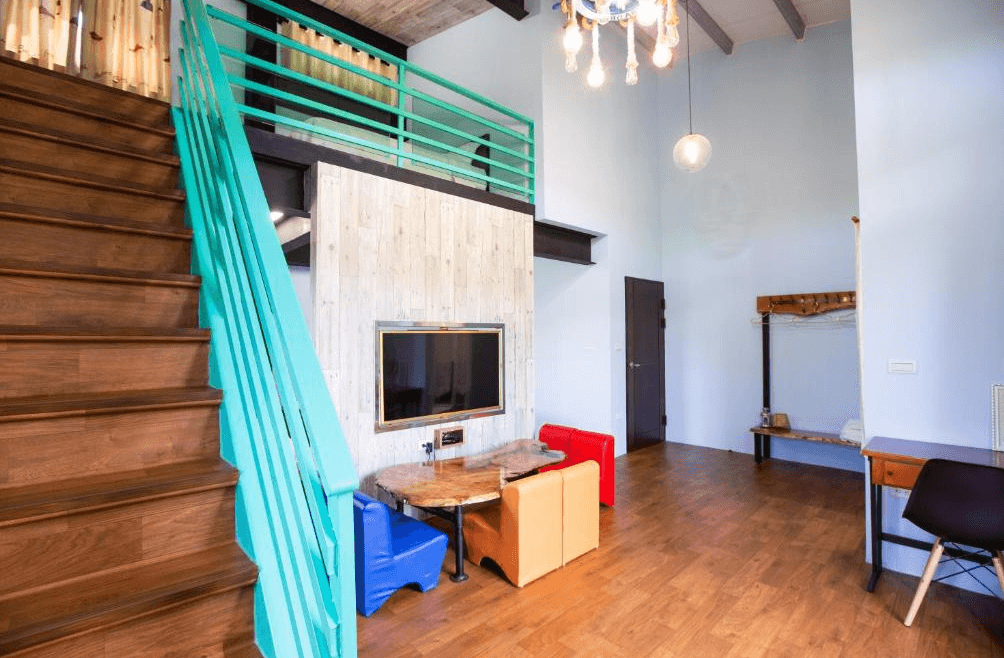 【玉里住宿】「吾笠塢民宿」親子樓中樓房型，設有木質樓梯、彩色沙發與大螢幕電視，挑高空間明亮寬敞。