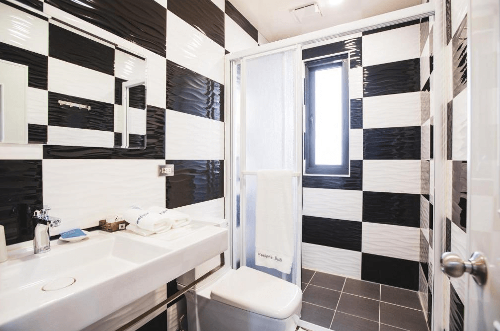 【玉里住宿】「吾笠塢民宿」浴室設計，黑白棋盤格磁磚風格，乾濕分離淋浴間搭配白色洗手台與盥洗用品。