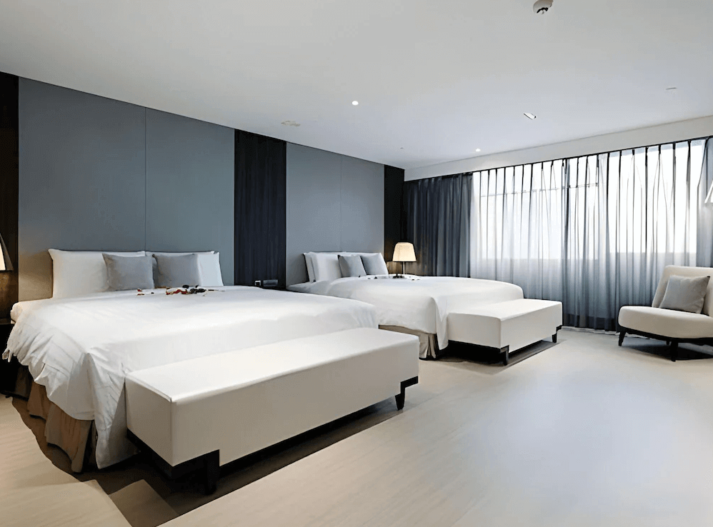 【高雄中央公園住宿】塔木德酒店高雄愛河館家庭房：設有兩張大床與現代簡約裝潢，大面落地窗搭配柔和窗簾，空間寬敞明亮。