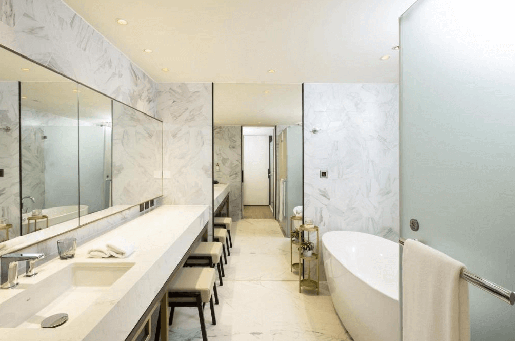 【高雄中央公園住宿】天成逸旅-舶寓高雄浴室：大理石紋理空間，配有獨立浴缸與長型洗手檯，搭配大片鏡面與柔和燈光，營造奢華舒適氛圍。