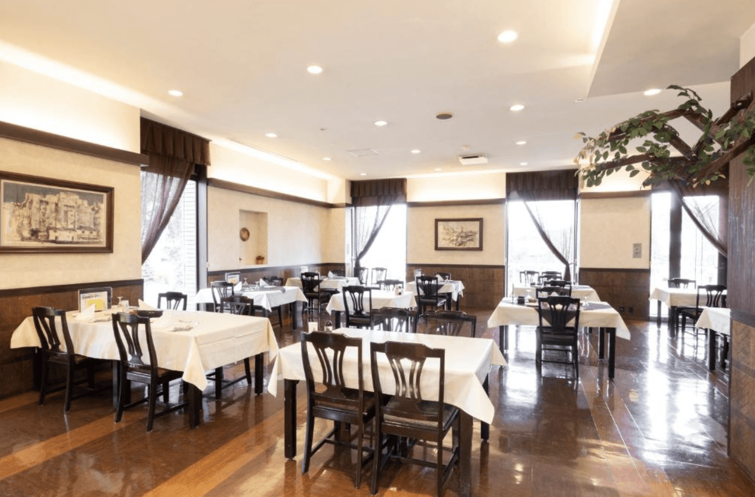 【富良野住宿】富良野度假飯店Edel Warme (Hotel Edel Warme) 餐廳空間，木質地板搭配白色桌布與典雅吊燈，環境明亮寬敞，適合享用餐點。