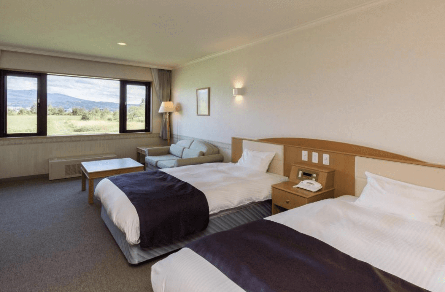 【富良野住宿】富良野拉漁村酒店 (Furano La Terre) 雙床房，房間設有大面窗景，可眺望遼闊田園與山景，內部配置沙發與茶几，空間舒適明亮。