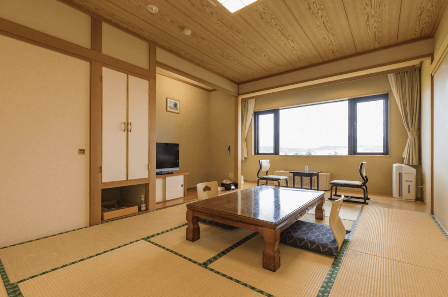 【富良野住宿】富良野拉漁村酒店 (Furano La Terre) 傳統日式榻榻米客房，木質天花與和室設計，配置矮桌與座墊，可透過大窗欣賞戶外景色。