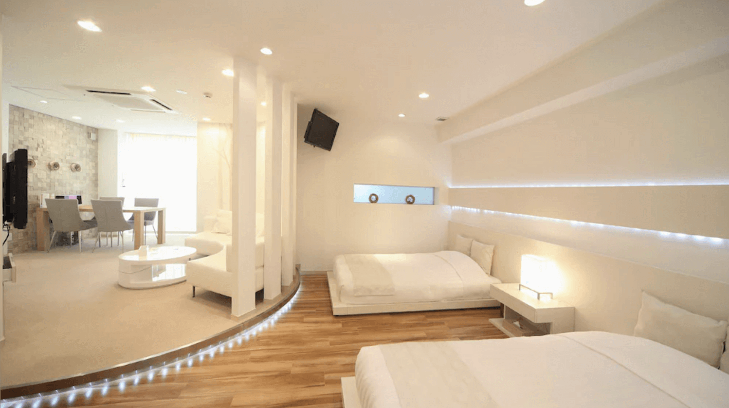 【富良野住宿】富良野自然森林飯店 (Hotel Naturwald Furano) 白色主題家庭房，室內明亮簡潔，配有多張床與客廳區域，燈帶點綴營造現代感。