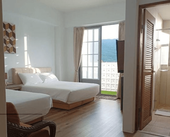 【玉里住宿】「小時公館城西」雙床房型，明亮木質地板設計，大片落地窗外可見山景與陽台，附設獨立衛浴。