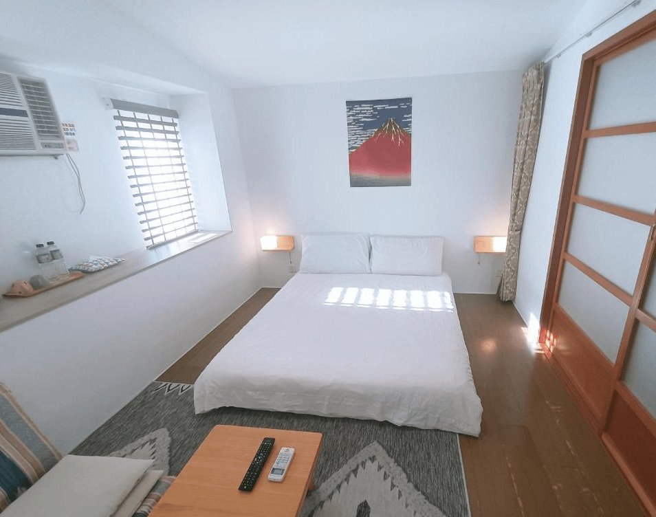 【玉里住宿】「小時公館城西」日式簡約雙人房，白色寢具搭配木質拉門與和風掛畫，房內擺放小茶几，營造清新舒適氛圍。
