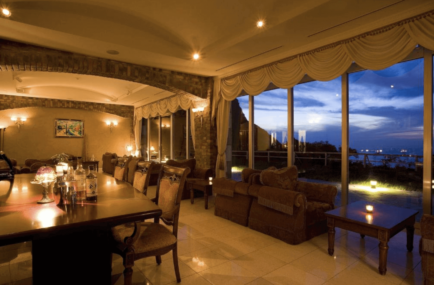 【小樽住宿】小樽城堡飯店 (Hotel Neuschloss Otaru) 酒吧休憩空間，落地窗外是日本海夕景，搭配典雅沙發與氛圍燈光。