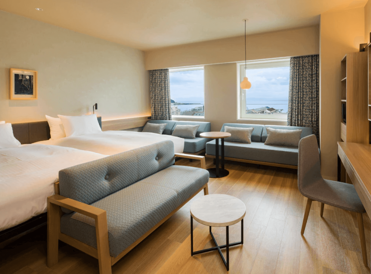 【小樽住宿】小樽格里茲頂級飯店 (GRIDS PREMIUM HOTEL OTARU) 雙床房，木質地板搭配淺色系家具，窗外可見小樽市區與港灣景色。