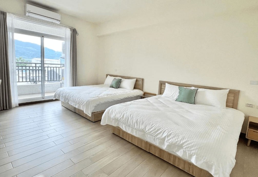 【玉里住宿】「小鳥散步玉里民宿」四人房，兩張雙人床搭配木質地板，落地窗外可見山景陽台，空間明亮舒適。