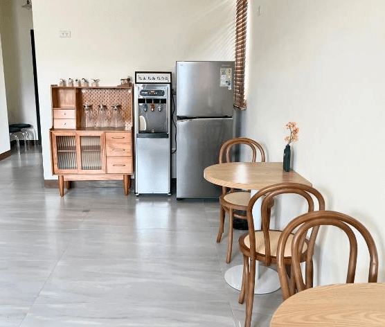 【玉里住宿】「小鳥散步玉里民宿」公共用餐與交誼區，設有木質桌椅、飲水機與冰箱，氛圍清新簡單，方便旅客休憩使用。