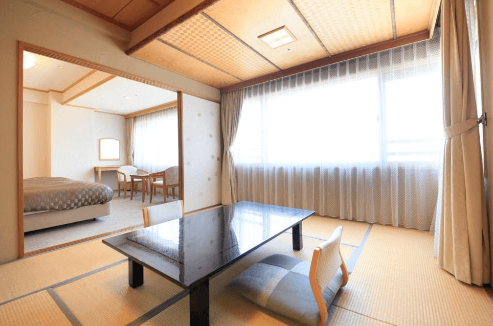 【函館住宿】平成館潮騷亭榻榻米房型，設有低桌與座椅，連接洋式臥室區域，大面窗戶帶來自然光線。