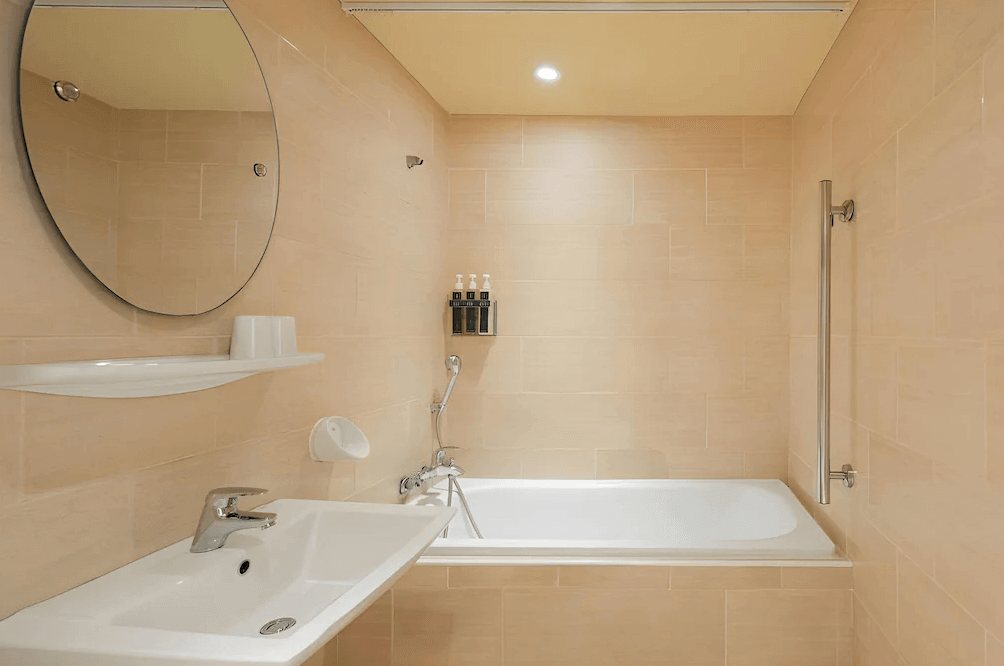 【鳳山住宿】康橋商旅五甲館浴室 乾淨明亮的浴室，配有浴缸、手持花灑與洗手台，牆面以淺色磁磚鋪設，設計簡約大方。