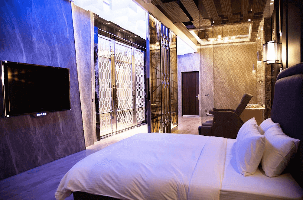 【鳳山住宿】御宿汽車旅館鳳山館 現代風客房設有大螢幕電視與舒適按摩椅，空間以藍紫色燈光點綴，營造摩登高雅的住宿體驗。