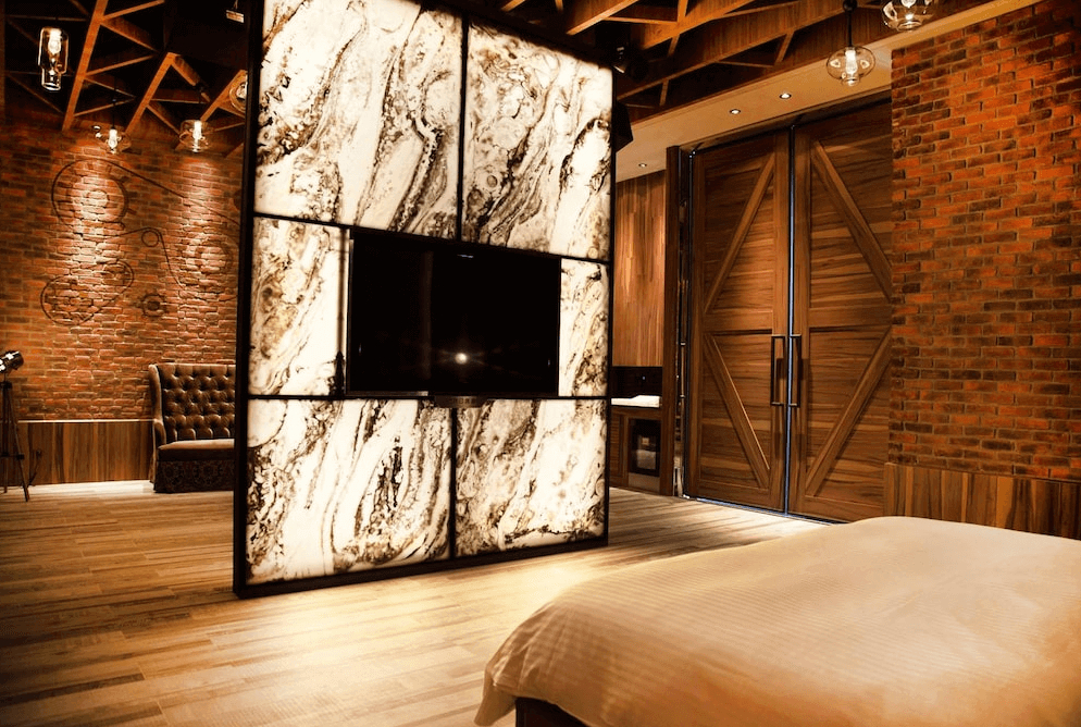 【鳳山住宿】御宿汽車旅館鳳山館 工業風套房紅磚牆搭配木質元素，設有大型電視與皮革沙發，房間氛圍獨特，融合工業風與現代設計。