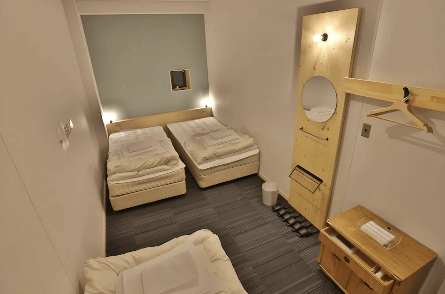 【富良野住宿】托馬爾旅館 (Hostel Tomar) 三人房型，設有兩張單人床與一張加床，木質簡約風格搭配鏡子與衣架，空間溫馨整潔。