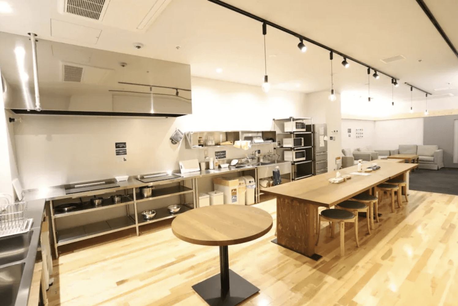 【富良野住宿】托馬爾旅館 (Hostel Tomar) 公共廚房與餐飲空間，寬敞明亮，配備多台微波爐、烤箱與料理台，並設有長桌和沙發休憩區。