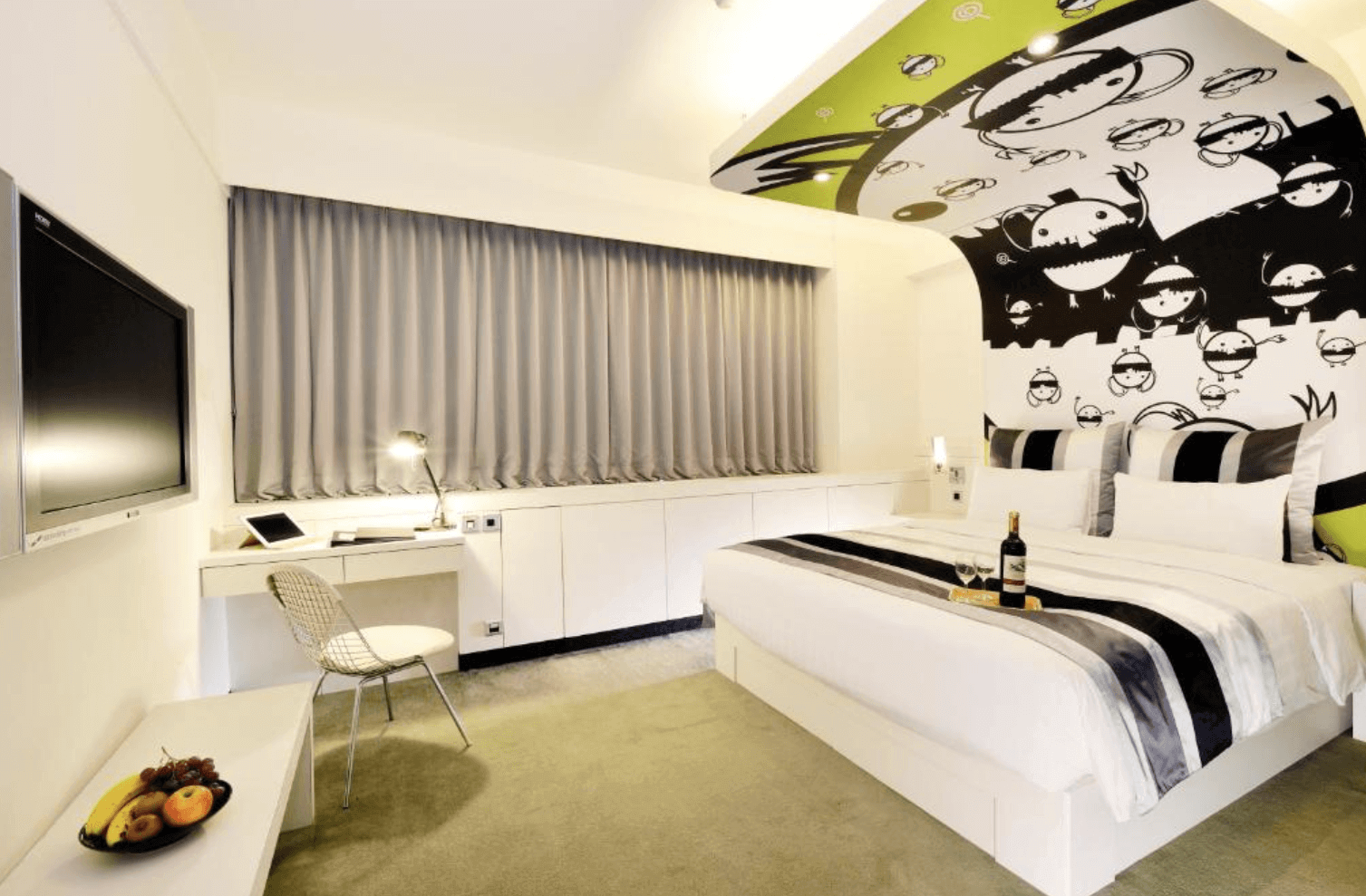 【前金住宿】承攜行旅高雄六合館 客房，設計以黑白與綠色卡通塗鴉風格為主，房內有大床、桌椅與電視，空間明亮活潑。
