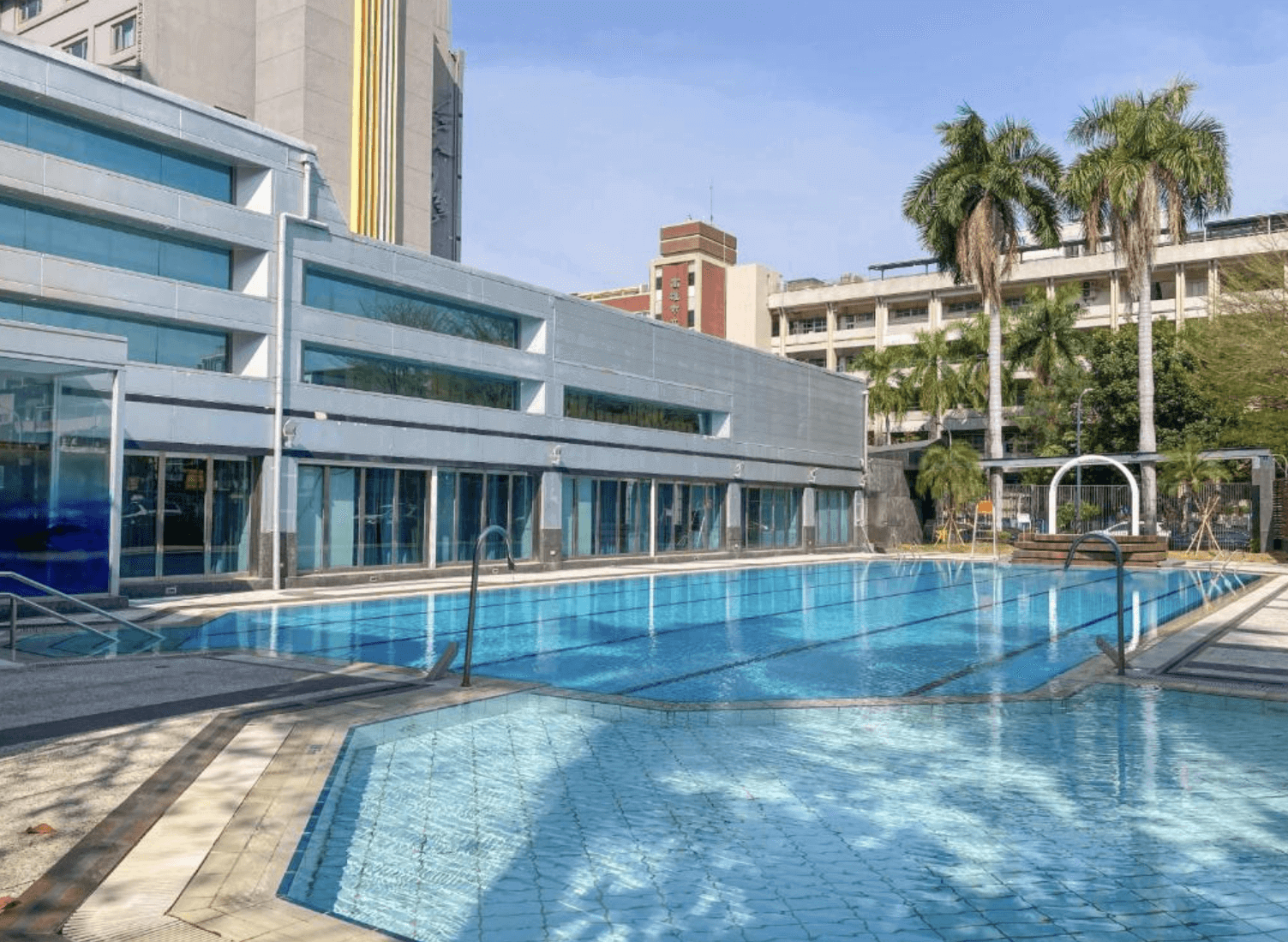 【前金住宿】承攜行旅高雄六合館 戶外泳池，設有成人與兒童池，周圍種有棕櫚樹，營造度假氛圍。