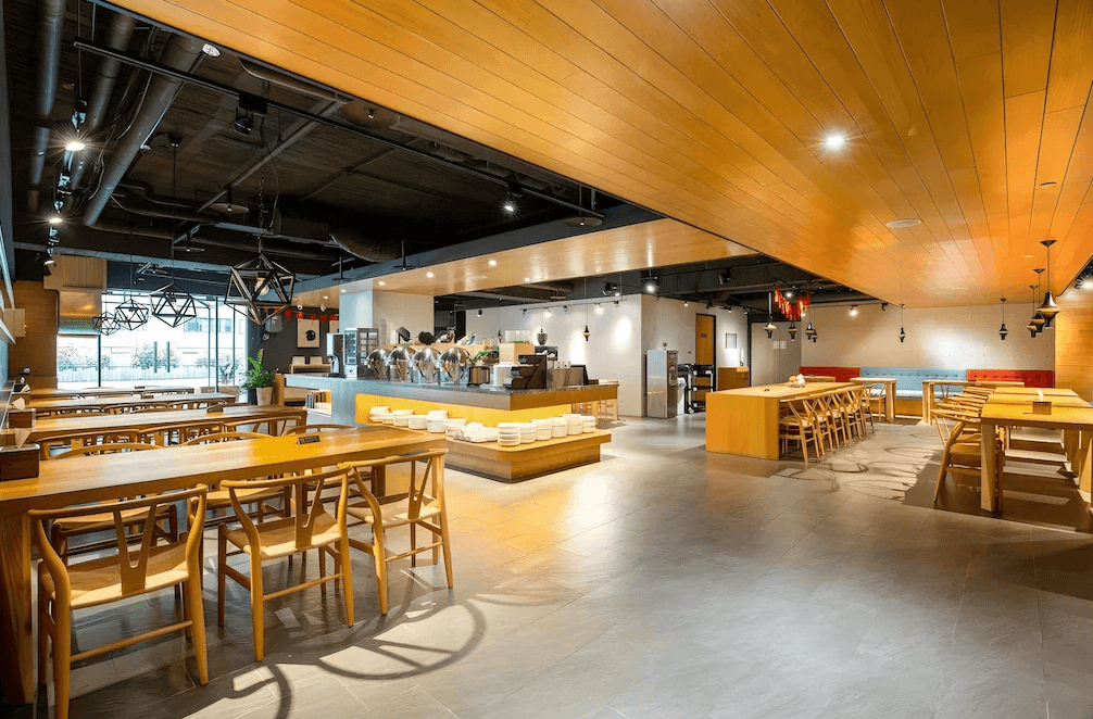 【三多商圈住宿】旅居文旅-亞灣館 餐廳空間：木質桌椅與現代吊燈設計，開放式取餐區，整體氛圍溫馨明亮，適合團體用餐。