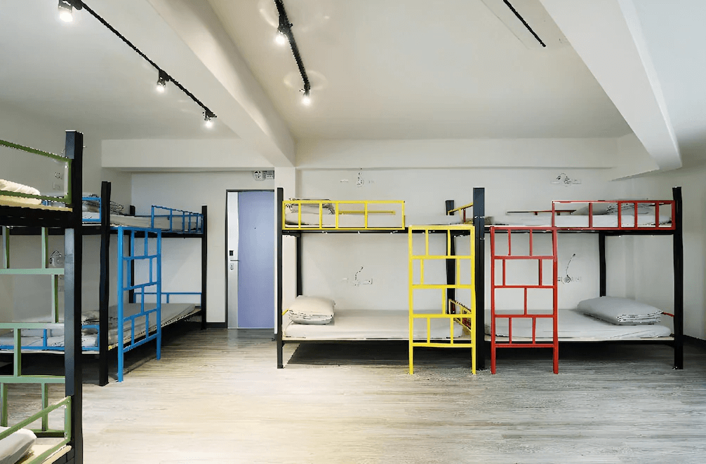 【三多商圈住宿】旅悅國際青年旅館多人房，整齊擺放彩色梯子的上下舖床位，空間寬敞明亮，適合背包客或團體住宿。