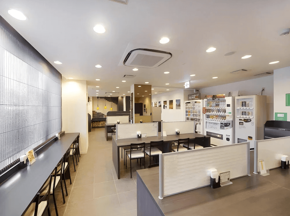 【旭川住宿】旭川超級酒店 (Super Hotel Asahikawa) 公共餐廳空間，提供開放式座位、自助販賣機，環境寬敞明亮，適合用餐與休憩。