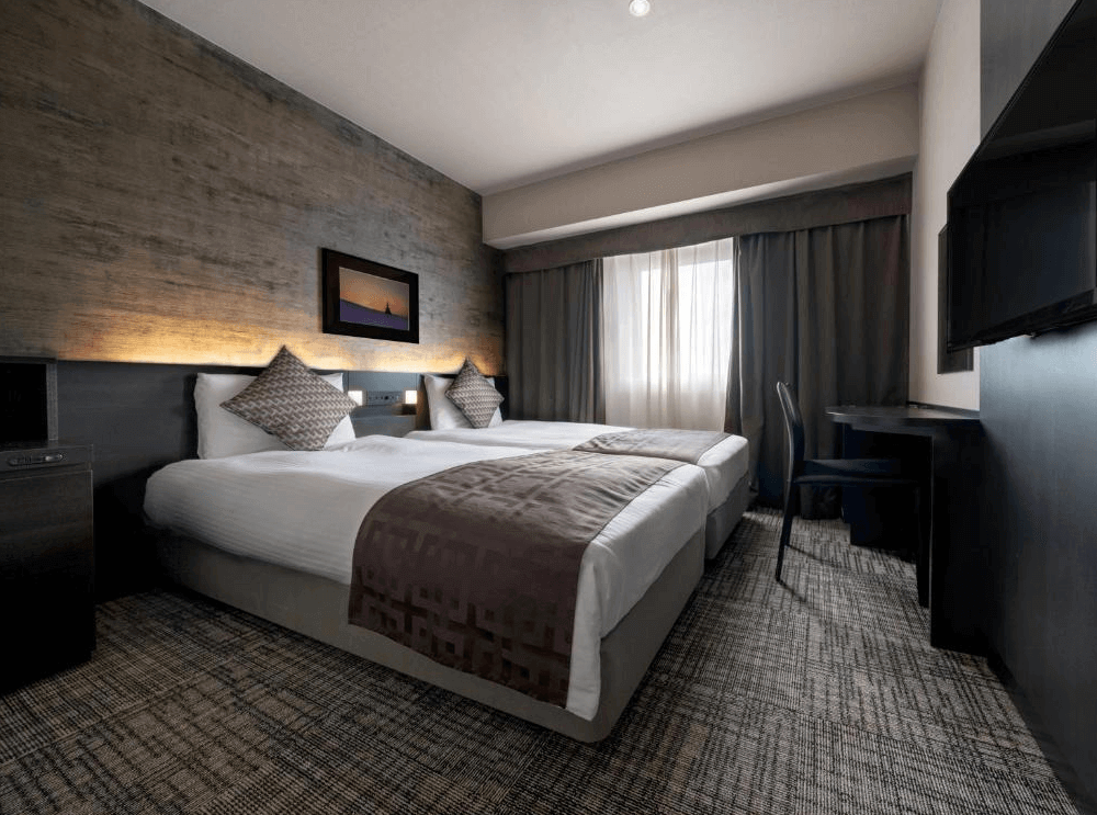 【旭川住宿】普樂美雅飯店-CABIN-旭川 (Premier Hotel CABIN Asahikawa) 雙床房，現代設計搭配深色木質牆面，兩張舒適單人床與大面窗戶，營造沉穩典雅氛圍。