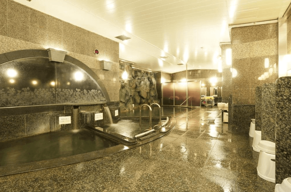 【旭川住宿】普樂美雅飯店-CABIN-旭川 (Premier Hotel CABIN Asahikawa) 大浴場，天然溫泉池與石造牆面設計，提供旅客舒適放鬆的泡湯環境。