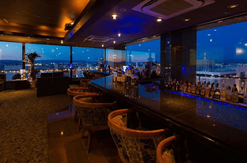 【旭川住宿】普樂美雅飯店-CABIN-旭川 (Premier Hotel CABIN Asahikawa) 高樓層夜景酒吧，環繞落地窗可欣賞旭川市夜景，吧檯擺滿多款酒品，氛圍高雅浪漫。