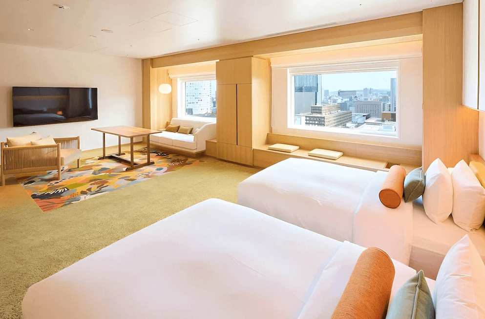 【札幌住宿】札幌京王廣場飯店 現代日式風格雙床房，大片落地窗可眺望札幌市景，室內配有沙發、木質桌椅與溫暖色調裝潢。