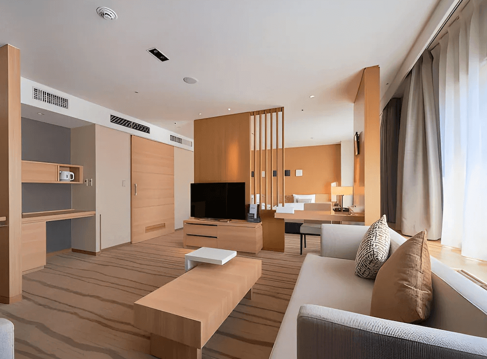 【札幌住宿】札幌京王廣場飯店 高級套房，開放式空間設計，設有客廳沙發區與書桌，木質元素搭配自然採光。