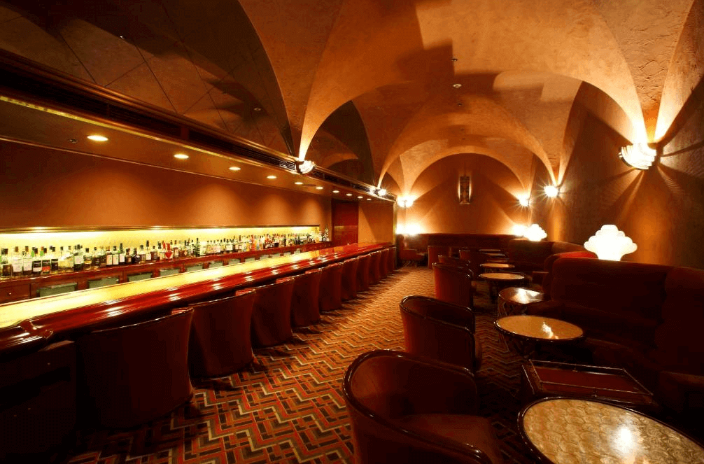 【札幌住宿】札幌京王廣場飯店 酒吧空間，拱形天花設計與昏黃燈光營造復古氛圍，長型吧台與舒適座椅排列整齊。