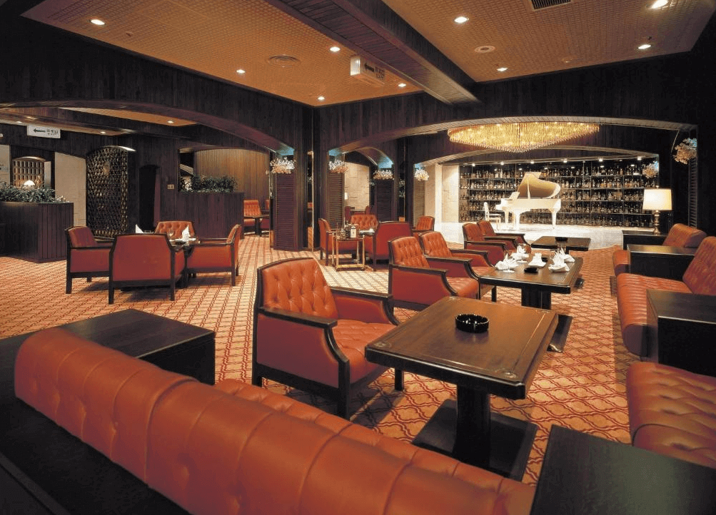 【札幌住宿】札幌公園飯店 酒吧休憩區，紅色皮革沙發搭配木質桌椅，舞台上擺設白色鋼琴，展現高雅氛圍。