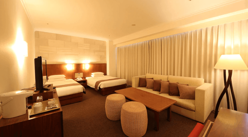 【札幌住宿】札幌朵蕾絲SPA度假飯店 溫馨雙床客房，房內設有大沙發與木質茶几，柔和燈光營造舒適氛圍。