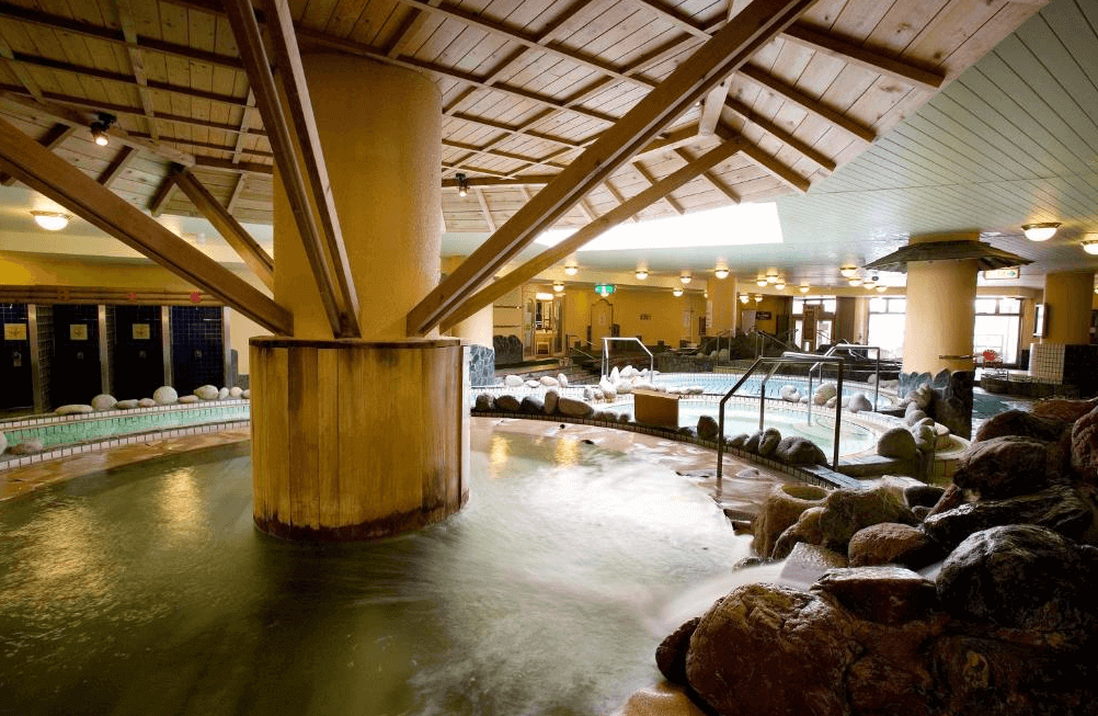 【札幌住宿】札幌朵蕾絲SPA度假飯店 溫泉池區，木質屋頂結合自然岩石造景，提供多樣泡湯池與放鬆設施。