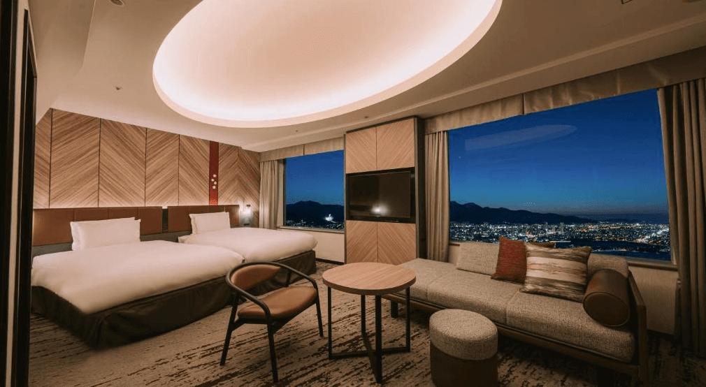 【札幌住宿】札幌王子大飯店 雙床房型，設有落地窗可俯瞰札幌夜景，房內備有沙發與圓桌，燈光設計溫馨大方。