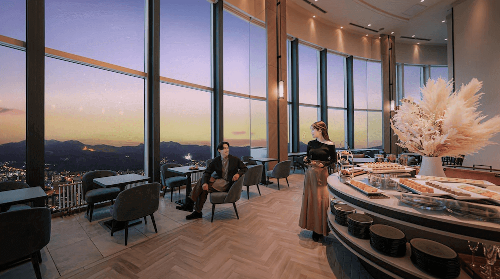 【札幌住宿】札幌王子大飯店 高樓景觀餐廳，落地窗外可欣賞夕陽與札幌城市全景，內部以優雅現代風格設計並提供甜點吧台。