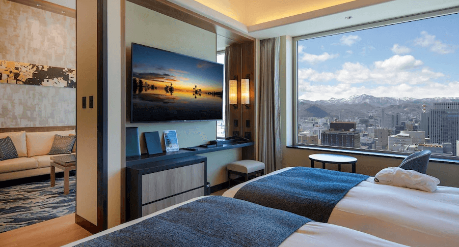 【札幌住宿】札幌蒙特利埃德爾霍夫飯店 豪華客房，雙床設計搭配大片窗景，可遠眺札幌市區與雪山美景。