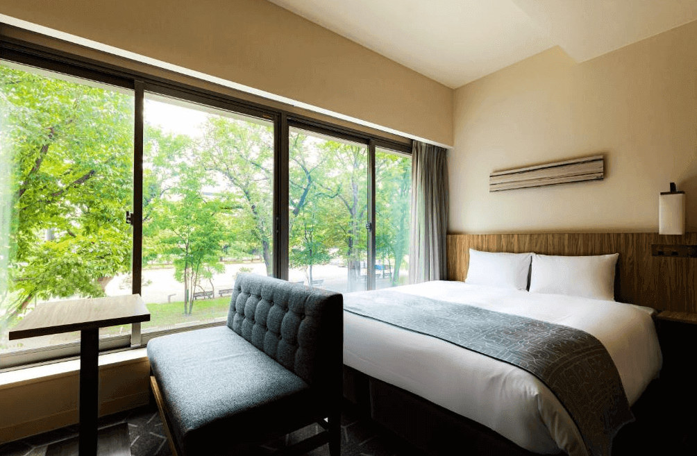 【札幌住宿】札幌豪景酒店大通公園 景觀客房，設有大床與長窗座椅，可直接欣賞大通公園綠意景觀。