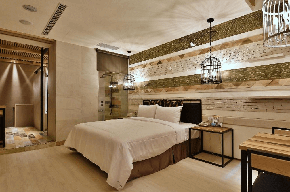 【鳳山住宿】歐閣精品汽車旅館-簡愛館現代雙人房房間以木質與幾何線條設計為主，大床搭配黑色床品，吊燈造型獨特，整體氛圍典雅沉穩。