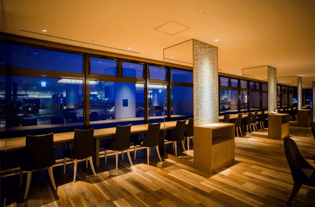 【函館住宿】湯之川渚太子酒店觀景休息區，大片落地窗可欣賞函館夜景，設有整排座椅與桌面，提供旅客靜心小憩。