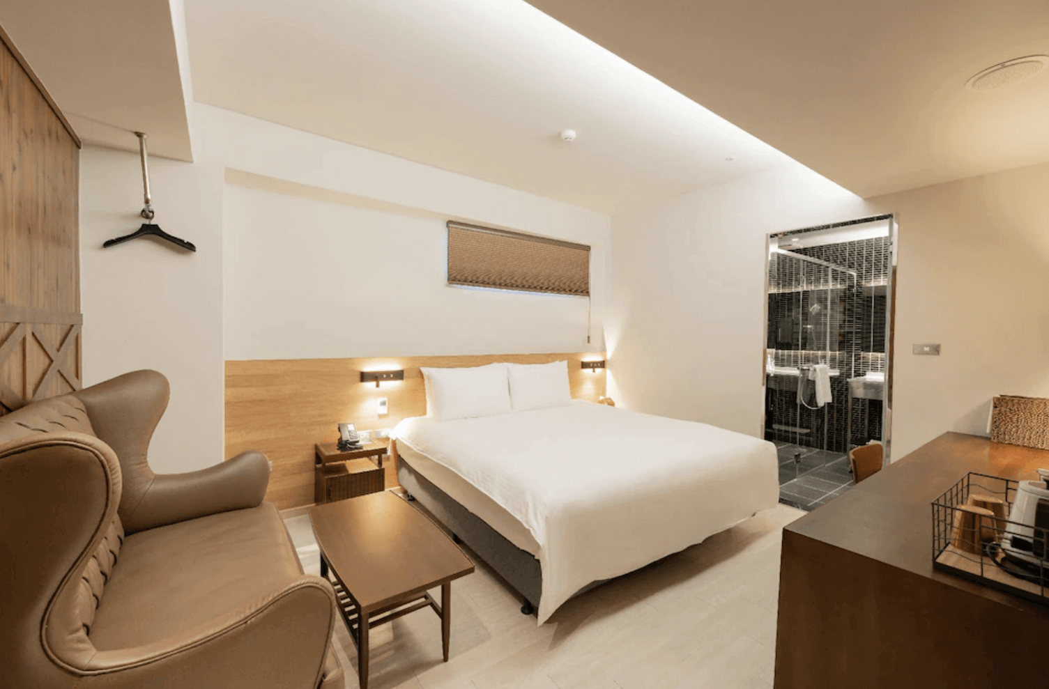 【前金住宿】高雄癮室 inns hotel — 溫馨雙人房：簡約木質設計的雙人房，內有大床、沙發與茶几，房內採光柔和，浴室採乾濕分離設計。