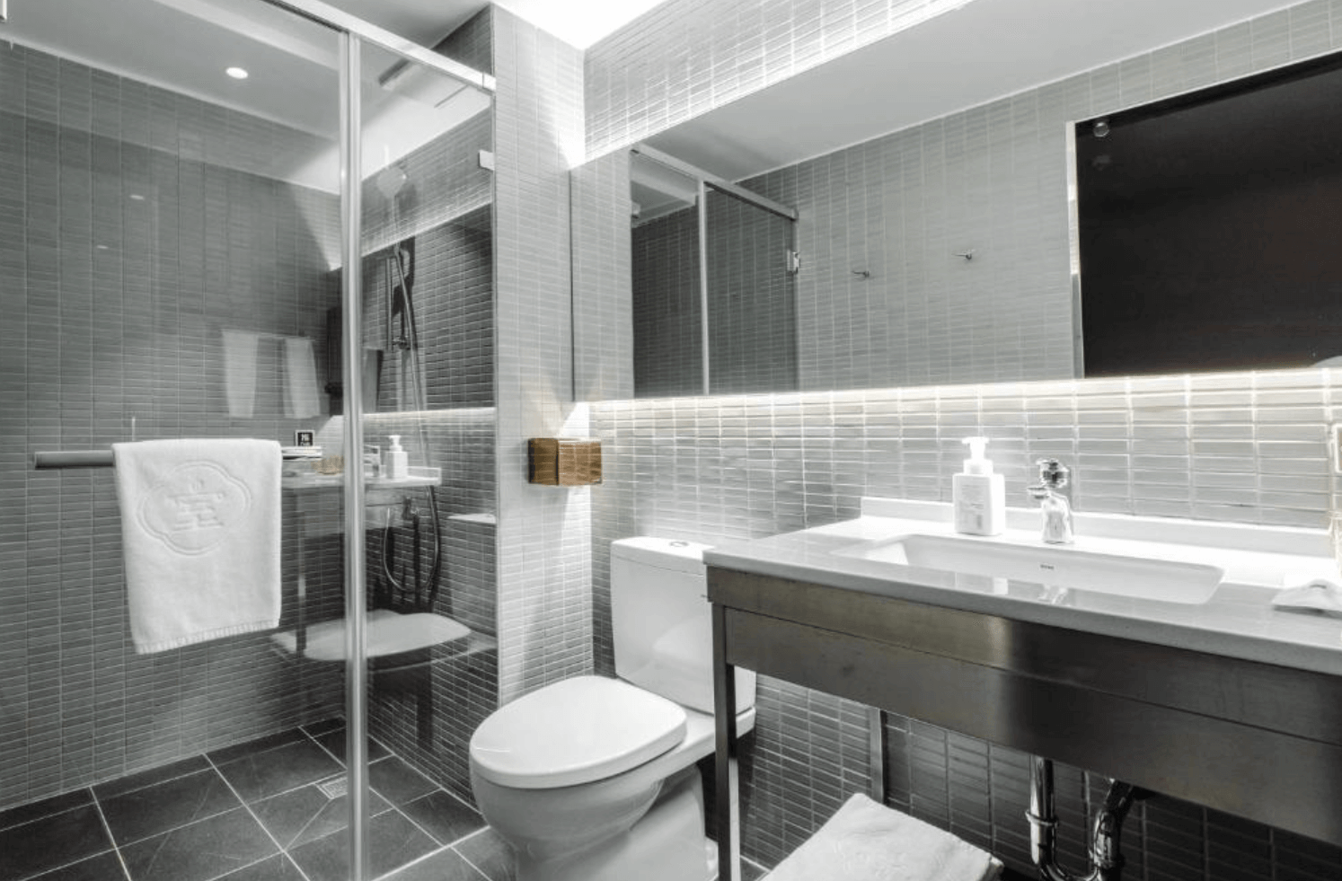 【前金住宿】高雄癮室 inns hotel — 衛浴空間：現代灰白磁磚設計，乾濕分離的淋浴間搭配洗手台，空間明亮整潔。