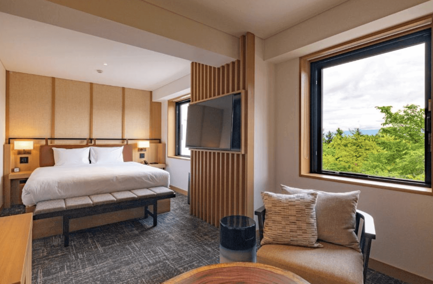 【富良野住宿】諾佐飯店雙人房：現代簡約設計的雙人房，大片窗戶可欣賞綠意盎然的景色，室內搭配木質元素與柔和燈光，舒適溫馨。