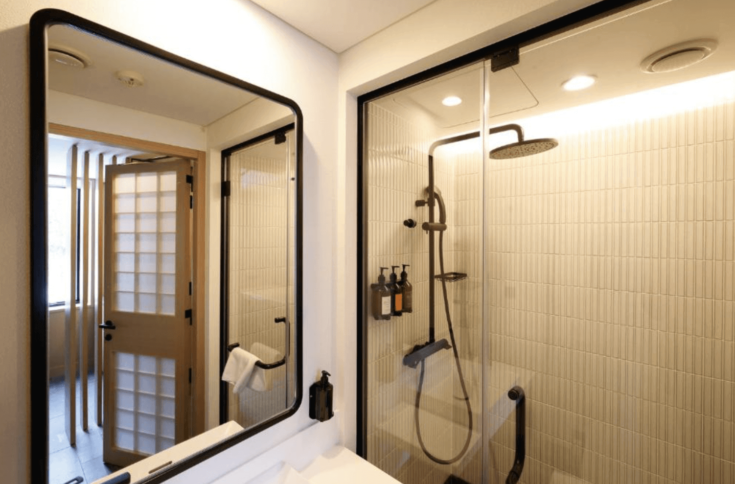 【富良野住宿】諾佐飯店浴室：現代化衛浴設計，淋浴間以玻璃隔間搭配淺色磁磚，提供齊全沐浴備品，乾淨明亮。