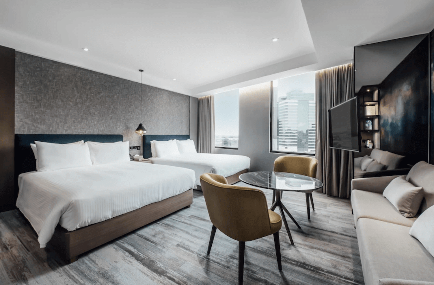 【前金住宿】鈞怡大飯店 現代設計客房，兩張大床、大片落地窗與市景視野，房內設有沙發、圓桌與電視，空間寬敞舒適。